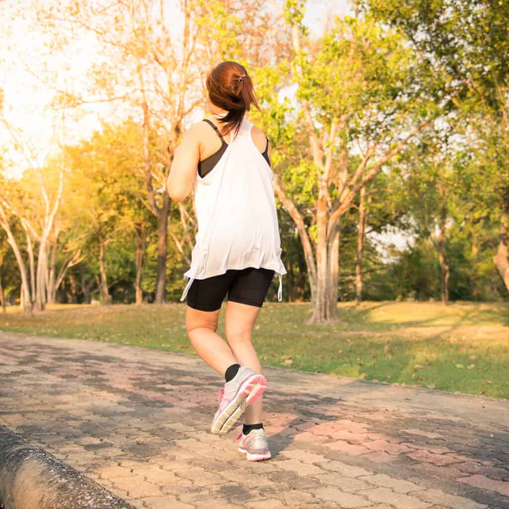 Young woman running in wood, training and exercising for trail r