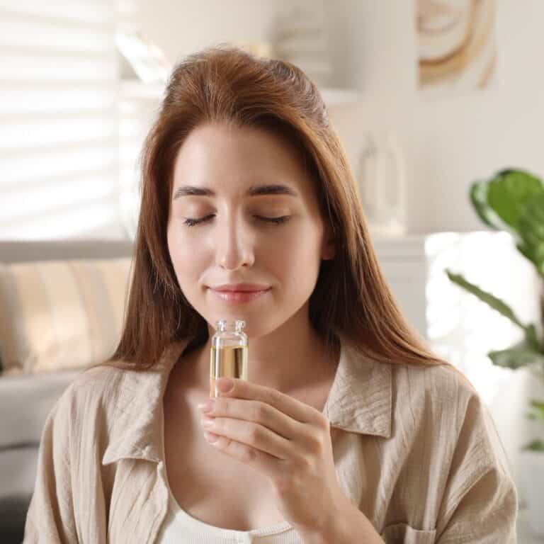 女性在家中嗅聞精油瓶口的香氣